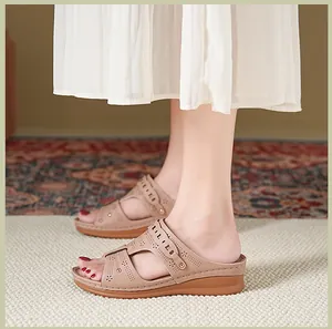 Close-up of beige wedge sandals featuring elegant laser-cut patterns and studs