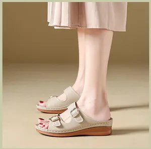 Elegant beige wedge sandals with dual buckles on model feet for a stylish summer look.