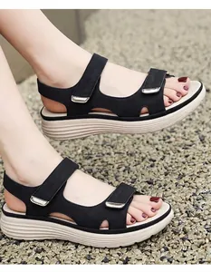 Close-up detail of women's black sporty sandals with magic tape straps on gravel ground