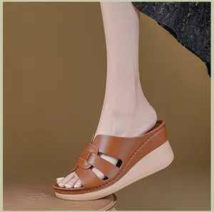 Detailed side view of brown leather wedge sandals with platform sole worn by a model