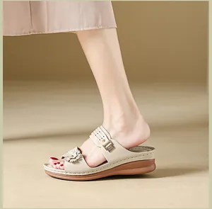 Side view detail of women's wedge sandals with elegant flower accent and stitching.