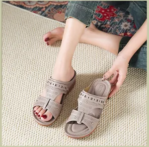 Detail view of taupe wedge sandals with laser-cut floral patterns and metal studs.