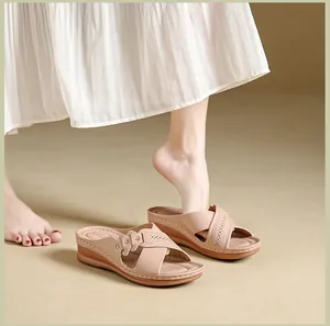 Close-up of apricot wedge sandals with perforated cross straps and floral accents.