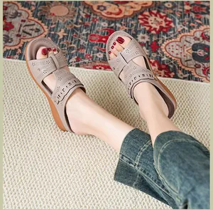 Close-up on-foot view of stylish beige wedge sandals with floral perforated pattern