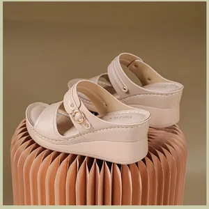 Close-up side view of elegant beige wedge sandals featuring gold buckles and stitching