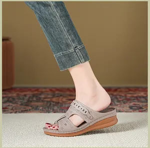 Close-up of taupe wedge sandal with laser-cut floral pattern on model foot.