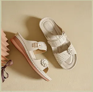 Detail view of beige wedge sandals featuring floral ornaments and perforated straps.