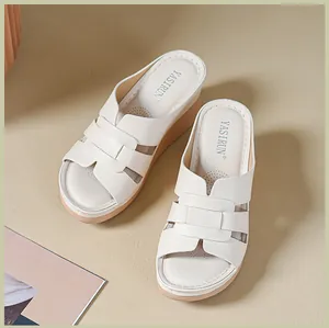 Detailed view of elegant white women's wedge sandals with soft stitched soles and logo.