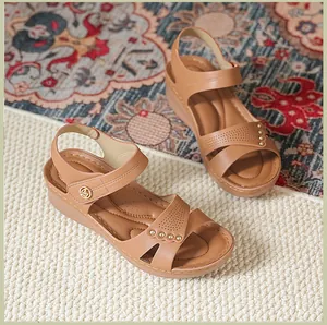Gros plan sur des sandales compensées marron avec clous et boucle décorative.