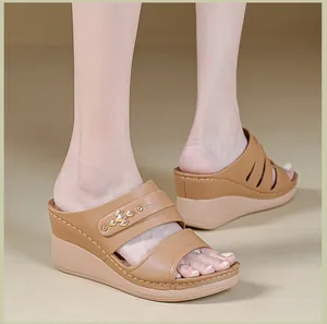 Close-up of brown wedge sandals with decorative metal rivet and contrast stitching.