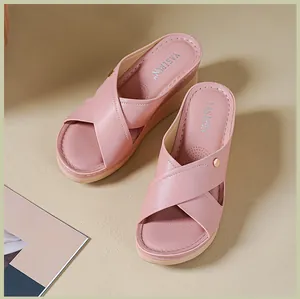 Détail de sandales compensées roses avec un design à brides croisées et bouton doré.