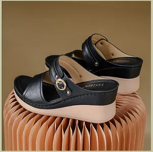 Detail view of black women's wedge sandals featuring elegant stitching and a gold buckle