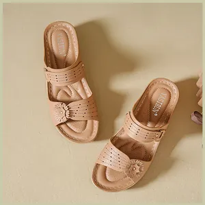 Detailed view of beige wedge sandals featuring elegant floral motifs and laser-cut patterns