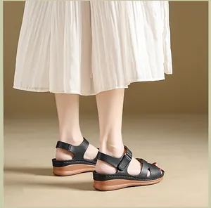Close-up of women's black platform wedge sandals styled with a white pleated skirt