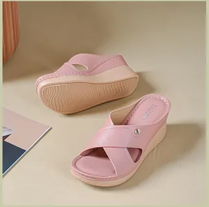 Détail de sandales compensées roses à brides croisées, semelle contrastée et antidérapante.