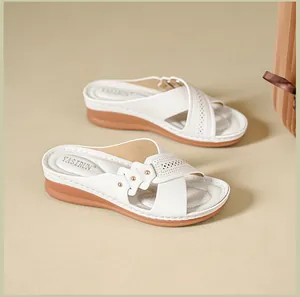 Detail view of white women's wedge sandals with perforated leather and soft footbed.