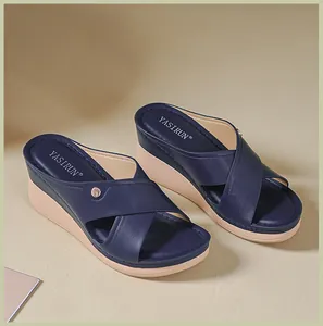Vue détaillée de sandales compensées bleu marine avec brides croisées et bouton doré