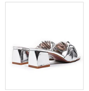 Detailed side view of silver metallic high heel sandals with elegant pleated straps