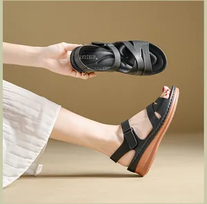Detail view of black wedge sandals with adjustable velcro straps and brown soles
