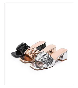 Detailed view of women's pleated metallic high-heeled sandals in silver, gold, and black
