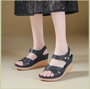 Elegant detail of women's black wedge sandals with crossover straps and gold studs.