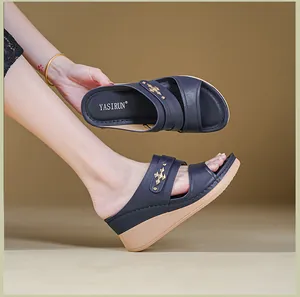 Side view detail of dark blue wedge sandals with decorative gold-toned hardware