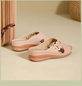 Close-up side view of beige wedge slippers with cut-out floral pattern and studs
