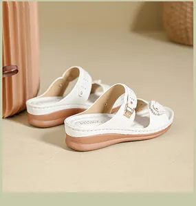Close-up detail of white floral wedge sandals featuring elegant floral accents and brown soles