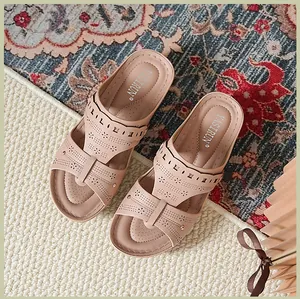 Detail shot of nude pink wedge sandals with laser-cut floral patterns and studs.