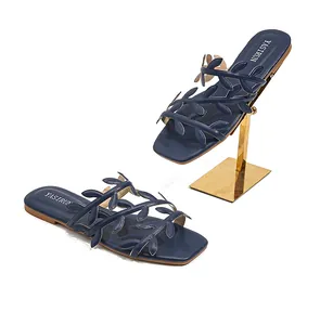 Detail of dark blue leaf-pattern strap design on stylish flat square-toe slides