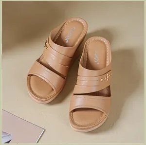Detailed view of brown wedge sandals with decorative studs and elegant stitch patterns.