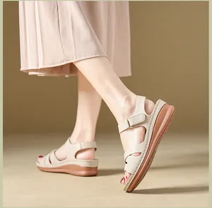 Close-up of beige wedge sandals with hook-and-loop strap on feet.