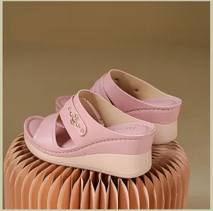 Detail of pink wedge sandals featuring golden stud accents on pleated paper stand.