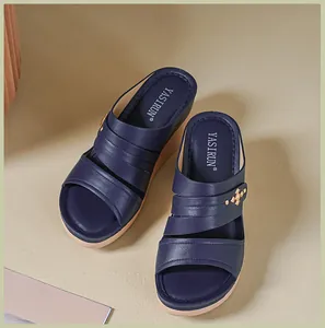 Close-up detail of navy blue women's wedge sandals featuring elegant cross-stitch design.