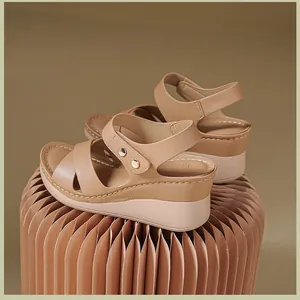 Detail view of khaki wedge sandals with metallic stud buckle and pleated pedestal.