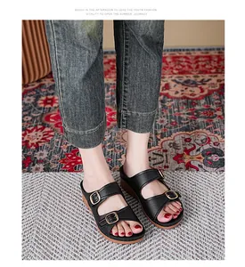 Close-up of black platform wedge sandals with gold buckle straps and open toe.