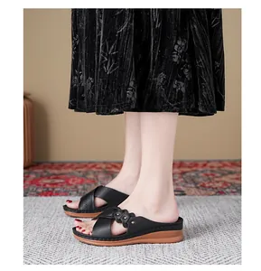 Side view detail of black wedge sandals with decorative floral straps on feet