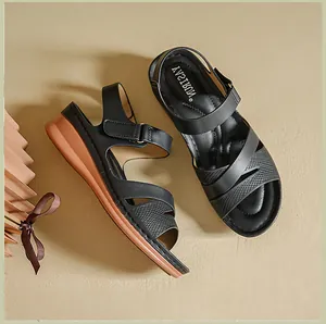 Detailed top-down view of black wedge sandals featuring adjustable Velcro straps and brown soles.