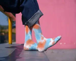 Calze a metà polpaccio tie-dye arancioni e blu mostrate sui piedi all'aperto.