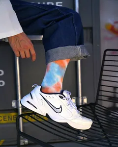 Primo piano dettagliato di calze tie-dye blu e arancioni con scarpe sportive alla moda.