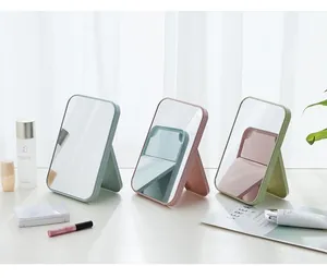 Trois miroirs de maquillage de table pliants colorés dans un décor minimaliste