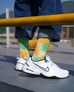 Dettaglio di calze sportive tie-dye gialle e verdi a metà polpaccio con scarpe
