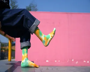 Dettaglio che mostra vivaci calze tie-dye verdi e arancioni indossate da un modello