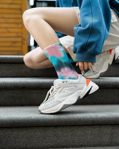 Primo piano di calzini tie-dye alla moda indossati con sneaker eleganti su gradini di pietra.