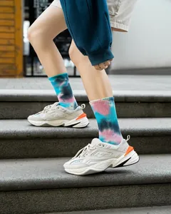 Inquadratura dettagliata di vivaci calzini tie-dye con sneakers bianche su gradini in pietra