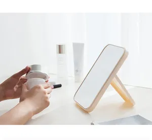 Grand miroir de maquillage pliable beige sur une coiffeuse blanche avec des soins