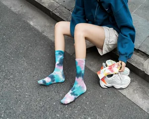 Dettaglio di calzini tie-dye vivaci indossati con sneakers in un contesto urbano.