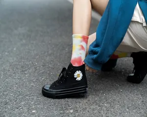 Dettaglio di calze a metà polpaccio tie-dye multicolore vivaci con scarpe alte nere.