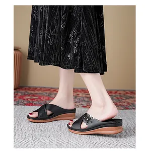 Detailed view of women's black leather wedge slippers with cutout design and studs