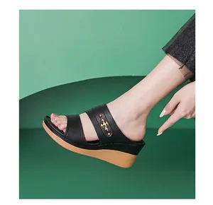 Close-up of black women's wedge sandals with gold decorative stud and brown sole
